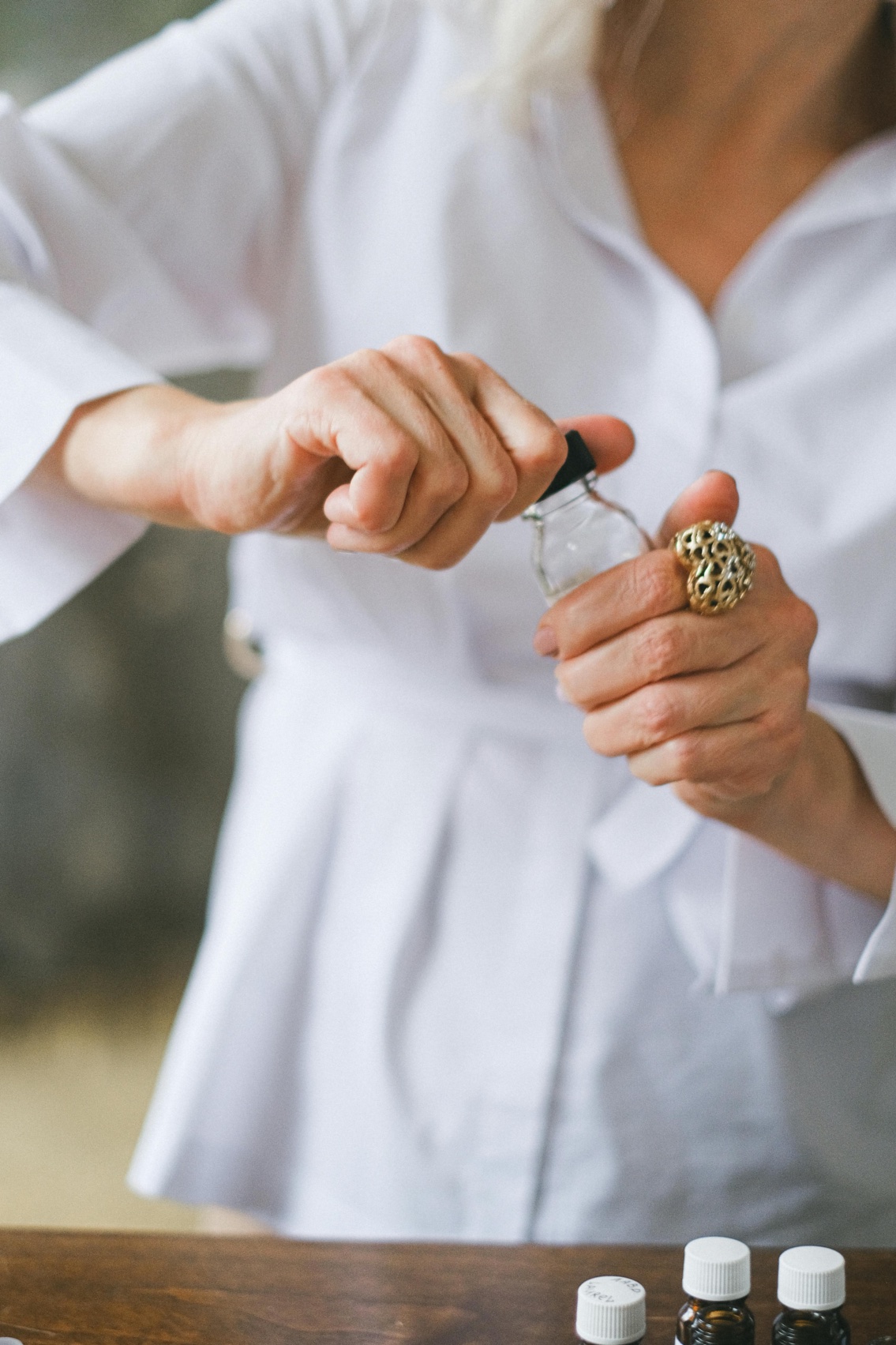 Woman in white lab coat opening a small glass vial.
